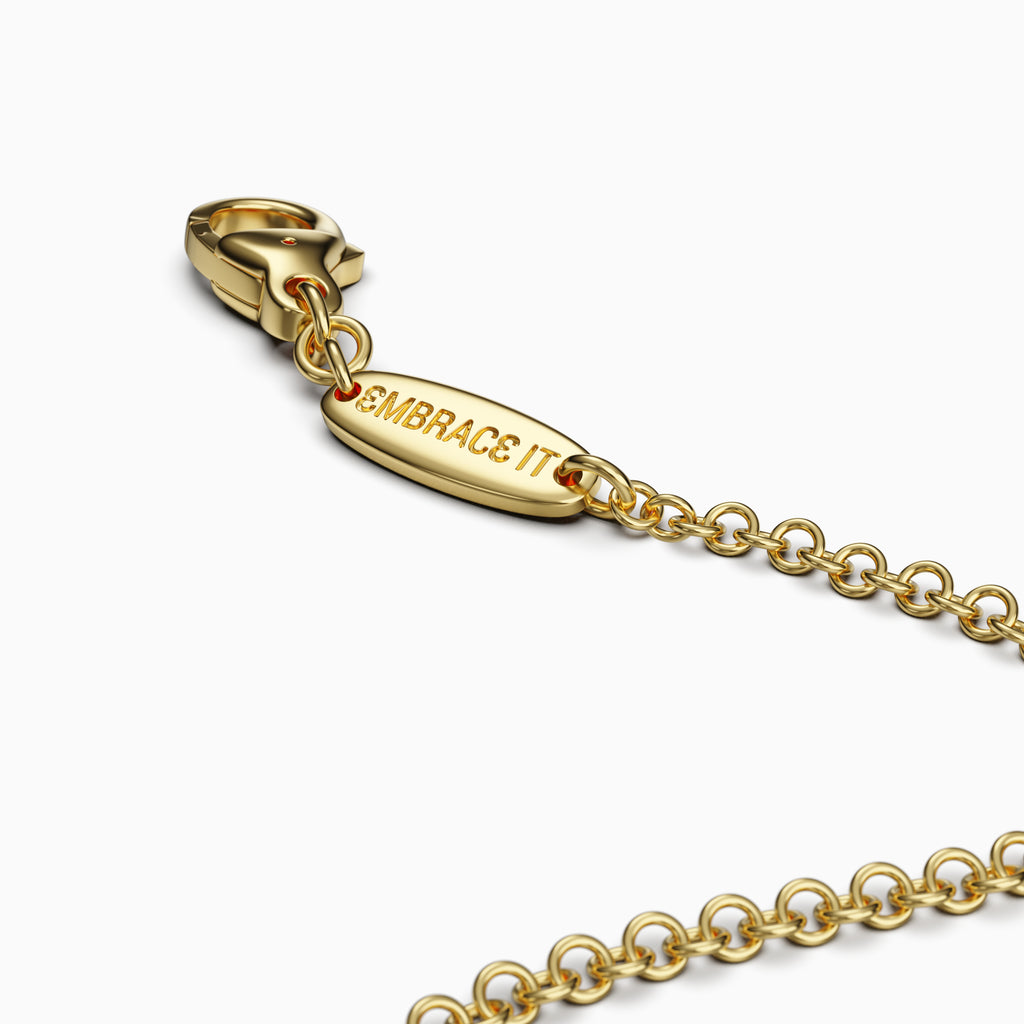 Gold bracelet with a lobster clasp and 'EMBRACE IT' tag on a white background