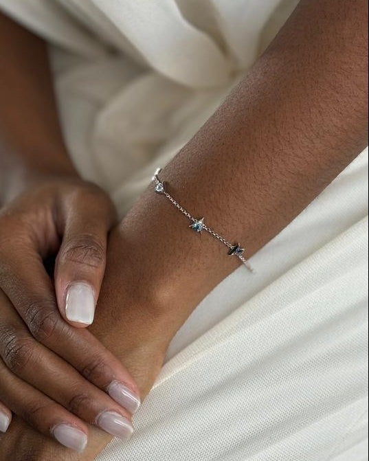Close-up of two hands with a silver chain bracelet against a white background