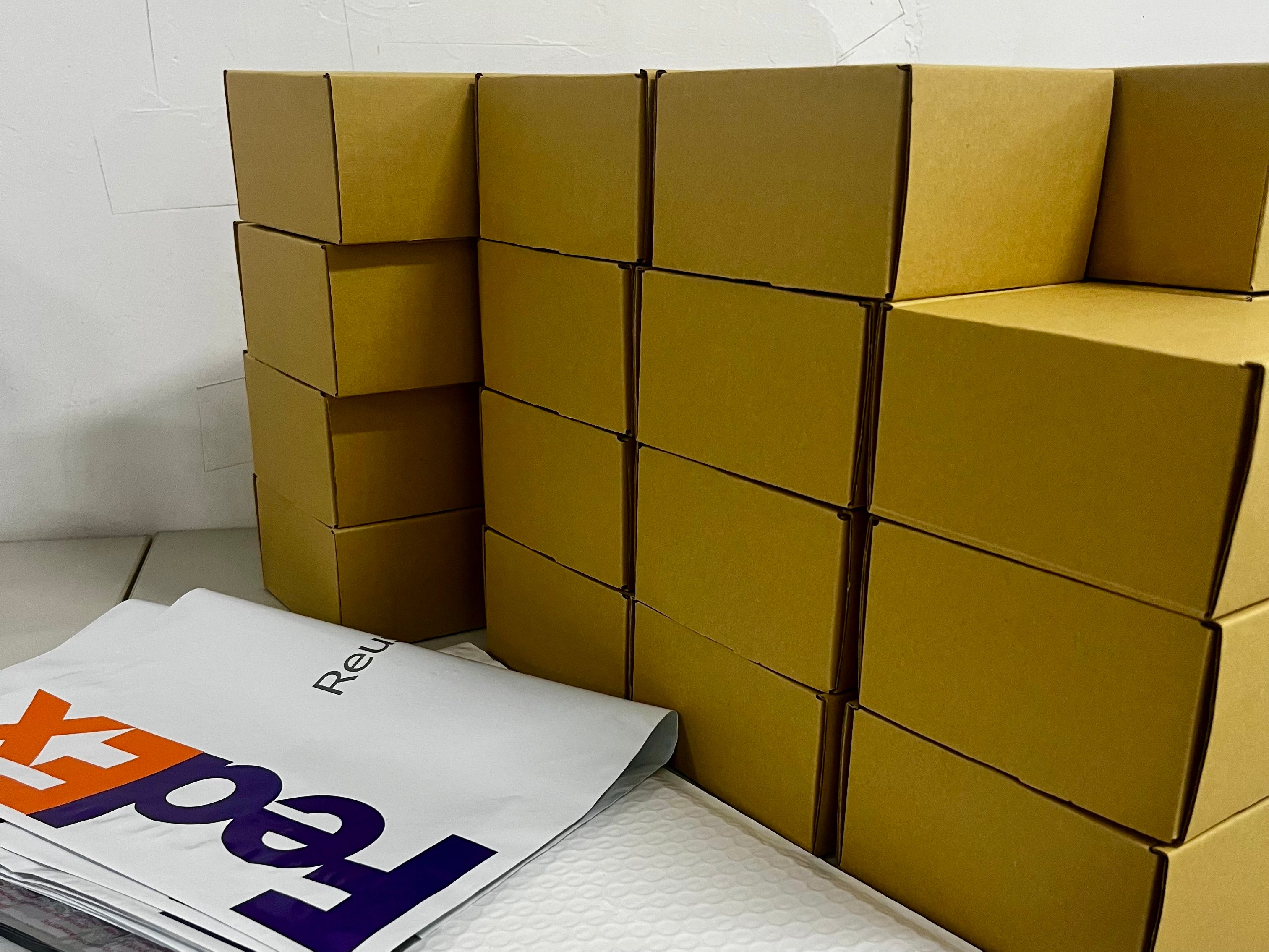 Stack of cardboard boxes with packaging materials on a white surface.