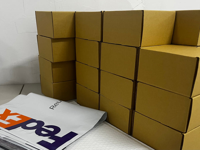 Stack of cardboard boxes with packaging materials on a white surface.