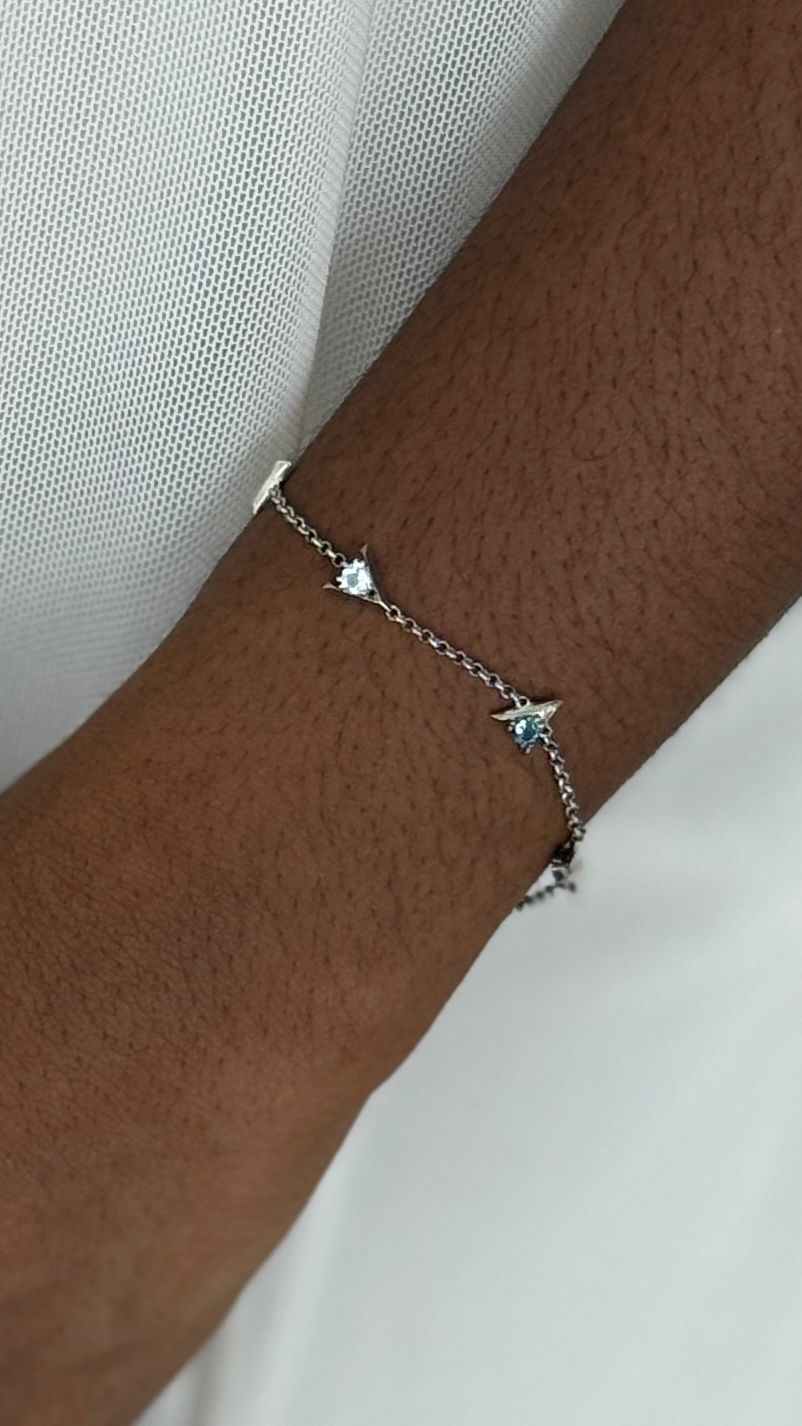 Silver Bracelet with "I am greater than my highs and lows" charms and blue gemstones on a wrist against a white background