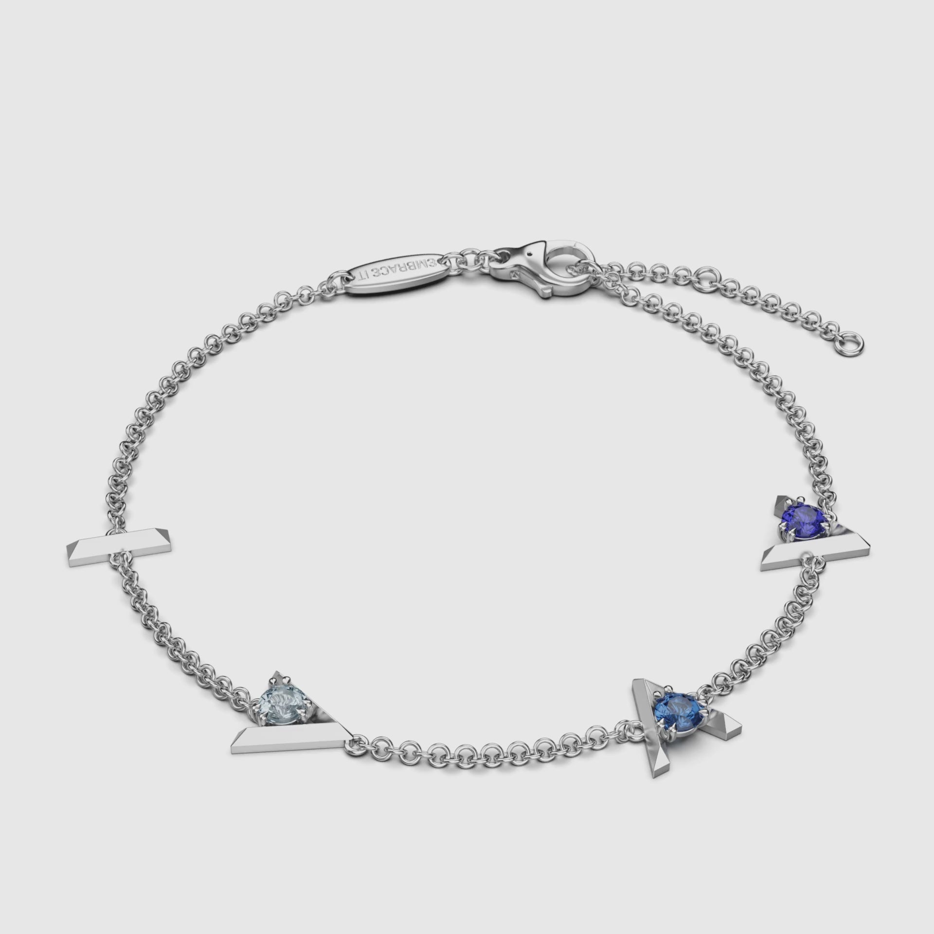 Silver chain bracelet with three different blue gemstones on a white background